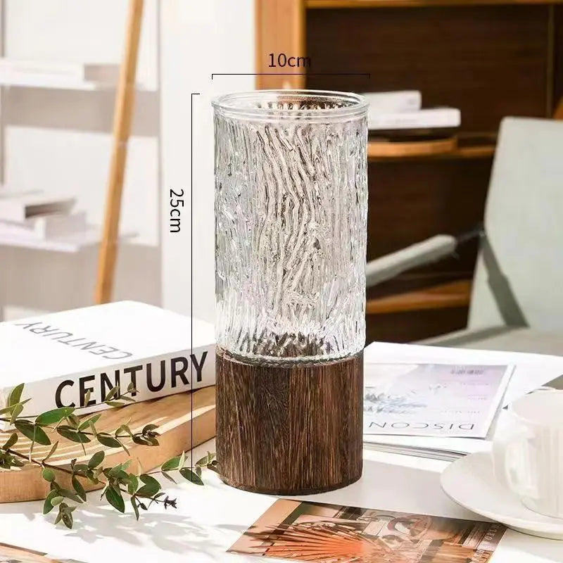 Two glass bud vases with wooden bases styled together on light linen table runner
