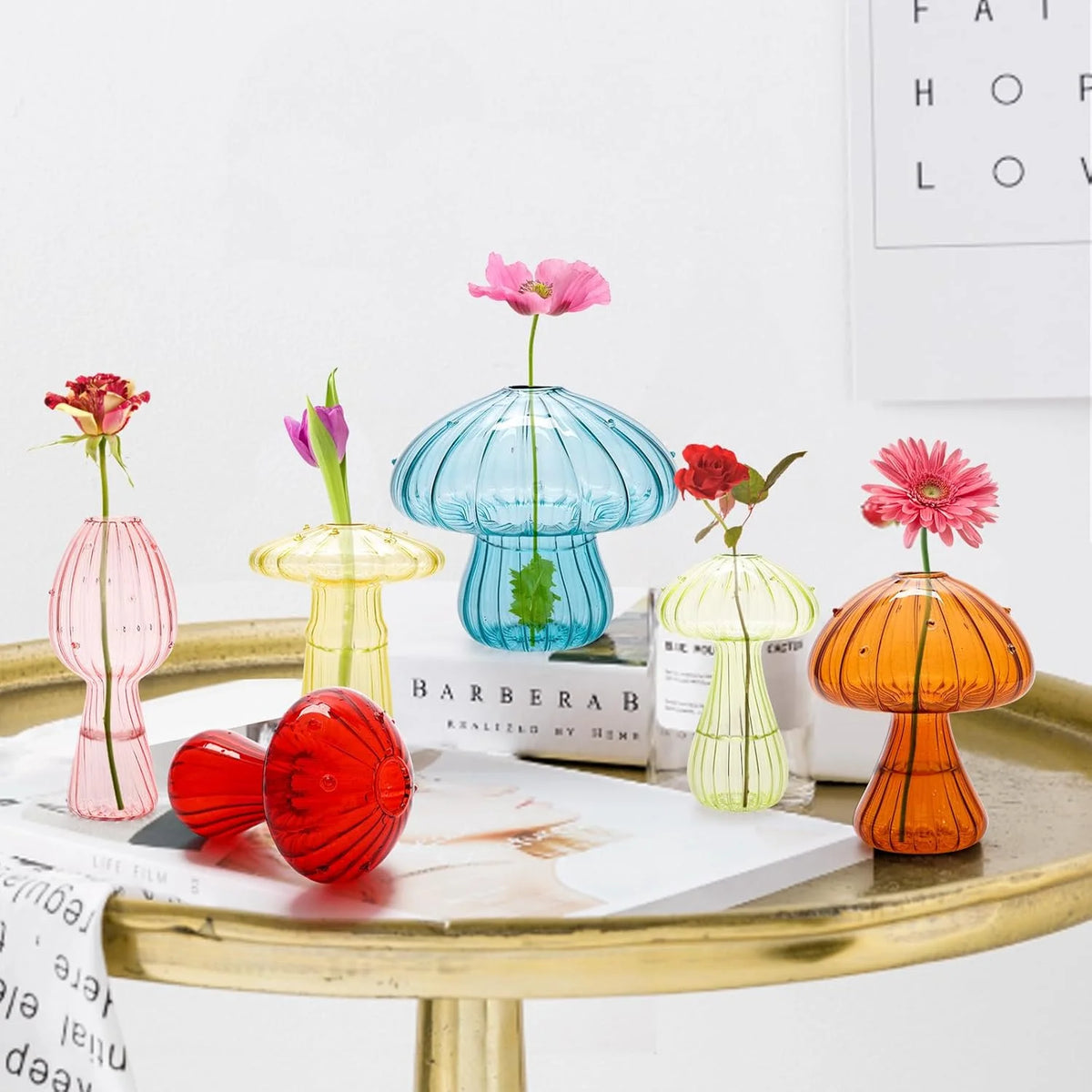 Three mushroom glass vases in red blue and brown on a shelf together