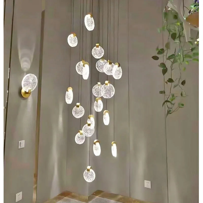 Golden crystal stair chandelier lit in warm light down a void
