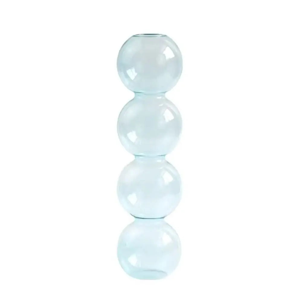 Small transparent glass hydroponic vase with white cotton stem on neutral linen surface