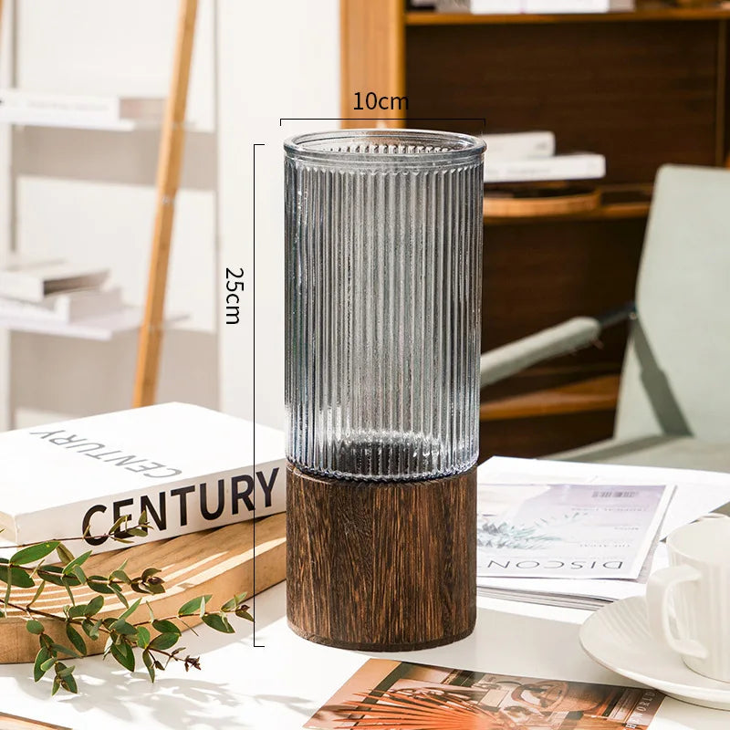 Glass bud vase with wooden base and water cutting on a modern bedside table