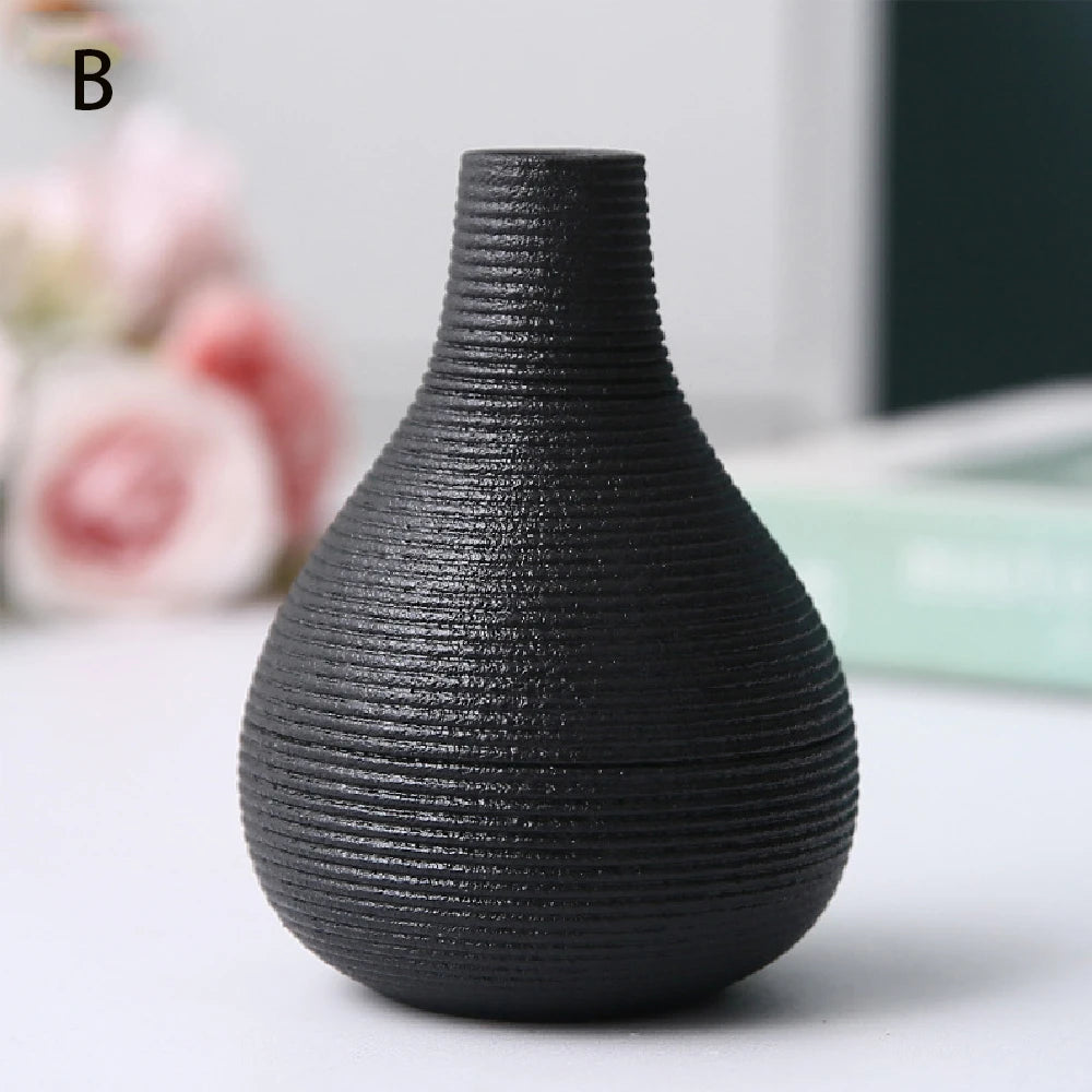 Black ceramic vase B holding single dried seed head on white floating wall shelf
