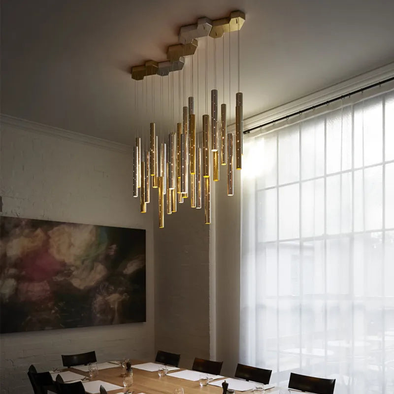 Silver bodied tube chandelier casting narrow downward beams of warm light