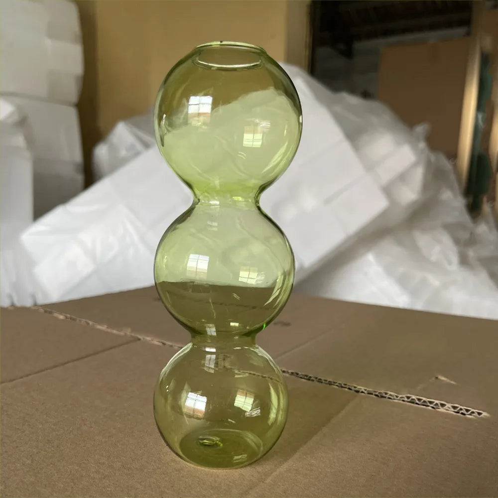 Blush pink glass hydroponic bud vase holding single stem cutting on romantic bedside table