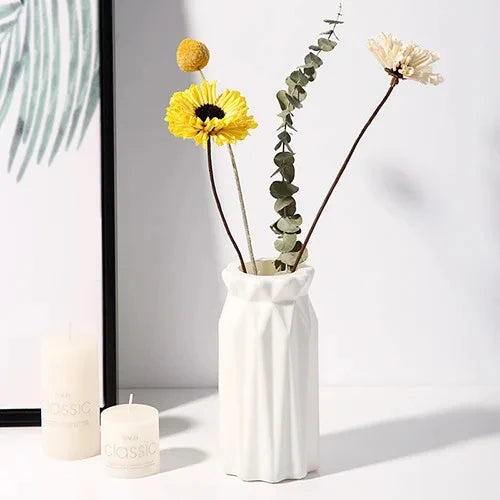 Top-down view of small white plastic Nordic vase on clean white surface