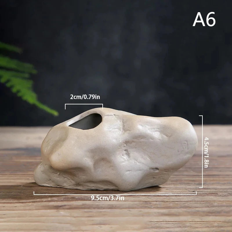 Two mini Zen stone ceramic vases on floating shelf with greenery surrounding them