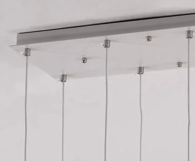Cold white light across the acrylic shades of a stair chandelier