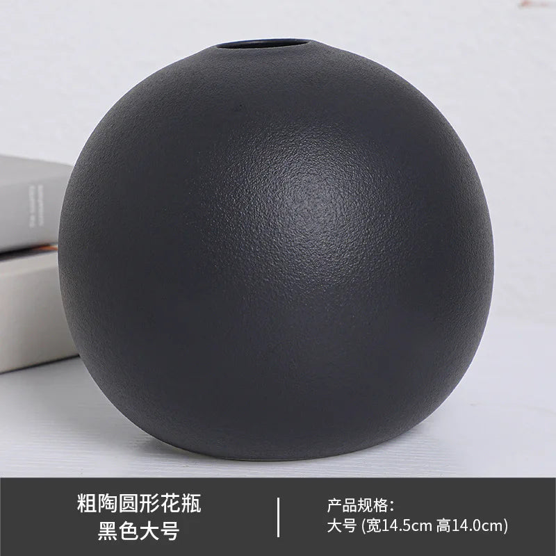 Black ball ceramic vase with single large white peony on console table