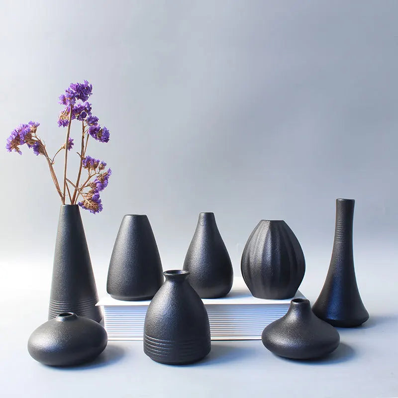 Simple Japanese ceramic small vase in matte black on wooden desk surface