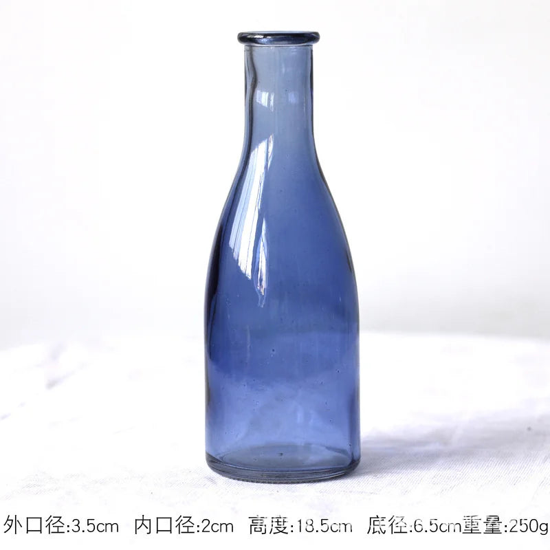 Red colored glass vase in group arrangement with other vases on shelf