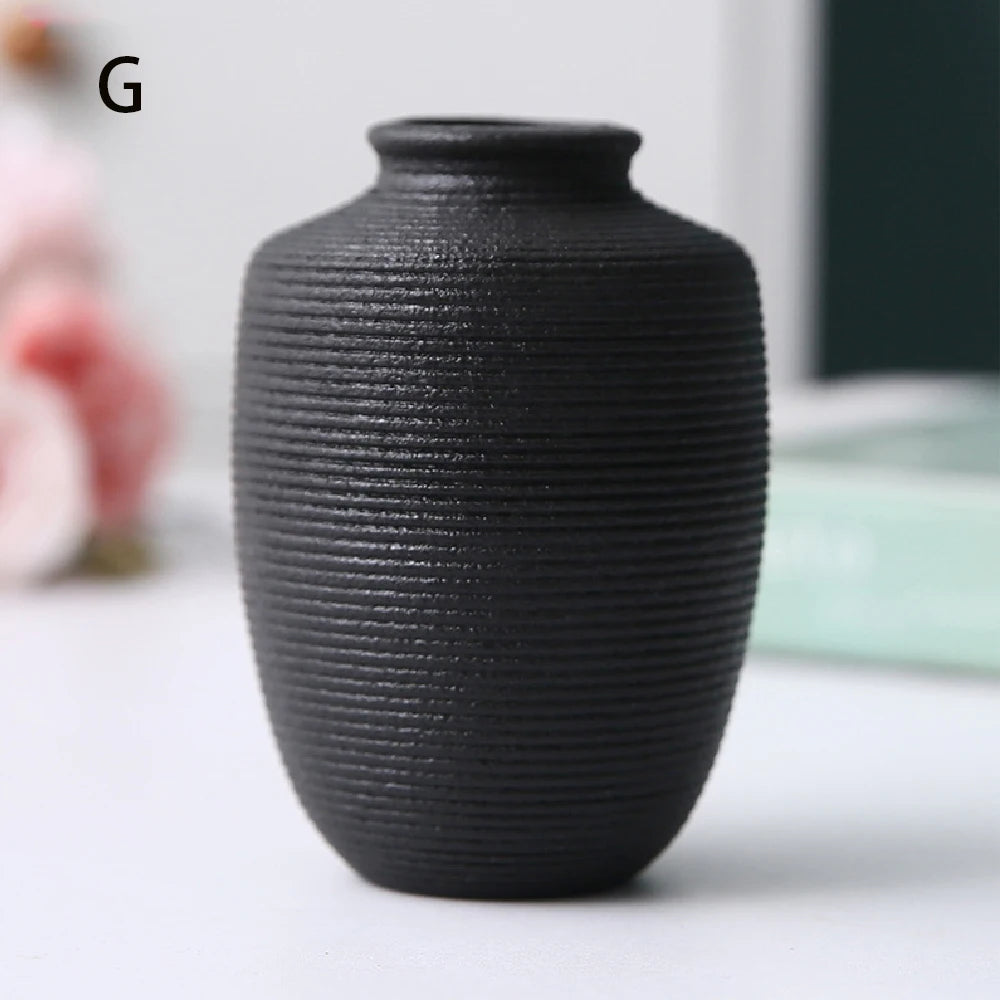 Small black ceramic vase C used as minimalist desk accent beside open notebook and pen
