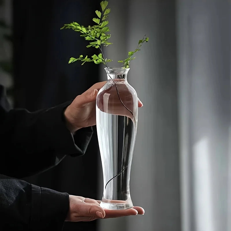 Close-up of clear glass cylinder vase opening with single white bloom inside