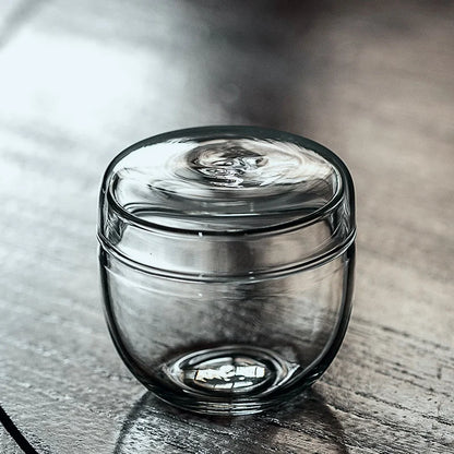 Glass bottle moss terrarium with small plant inside on home desk