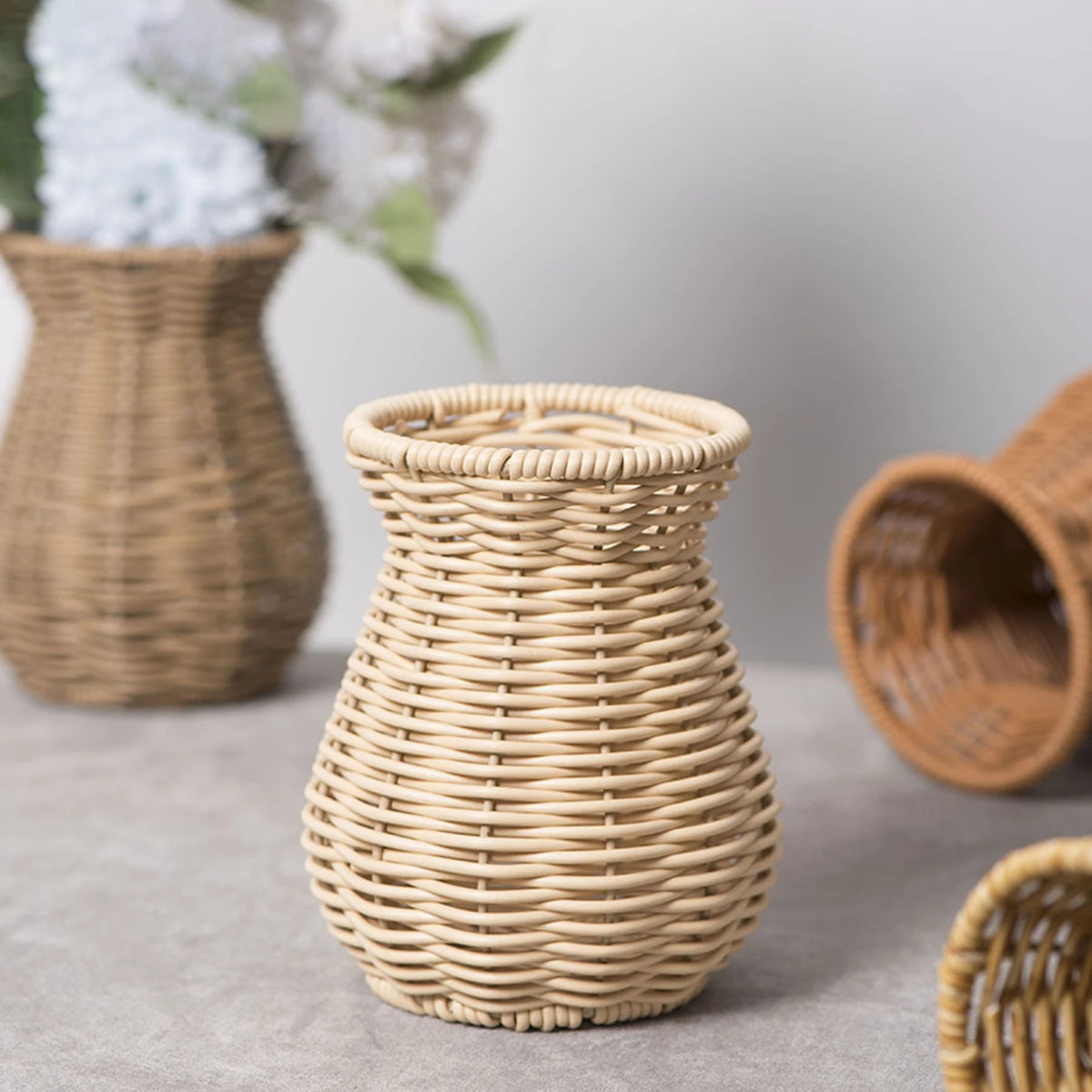 Woven rattan plastic vase style B holding dried botanicals on a coastal sideboard