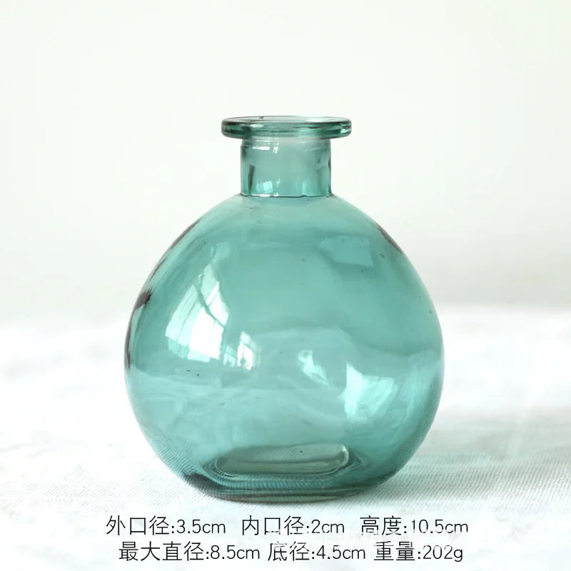 Two green glass terrarium vases of different sizes on white bookshelf
