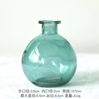 Two green glass terrarium vases of different sizes on white bookshelf