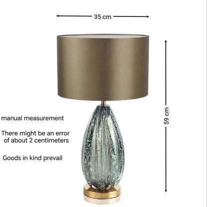 Modern glass table lamp switched on casting diffused light in bedroom
