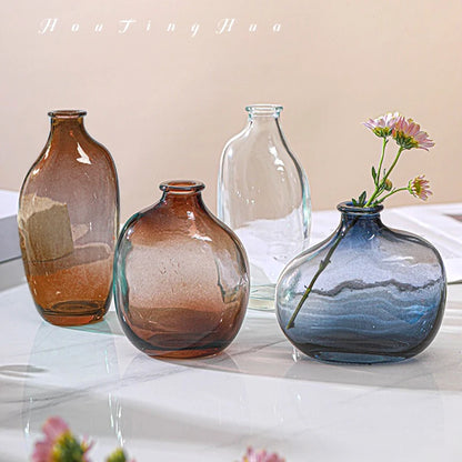 Brown retro glass vase with flower stems on wooden desk