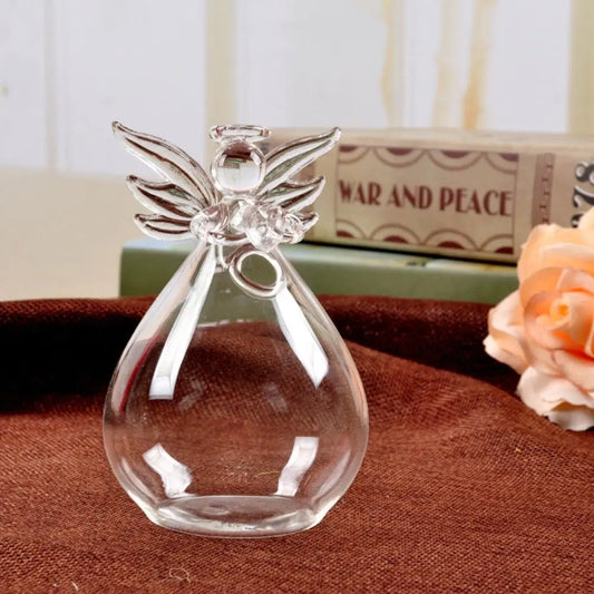 Small glass angel vase hanging on white wall with fresh flower stem