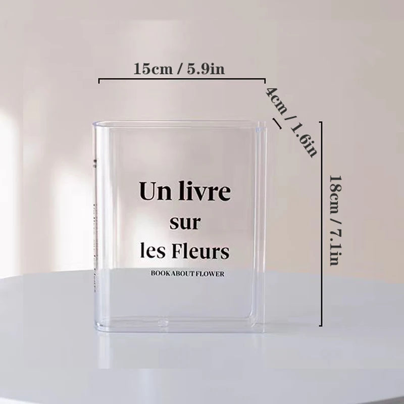 Acrylic book-shaped vase on white shelf between actual hardcover books as creative accent