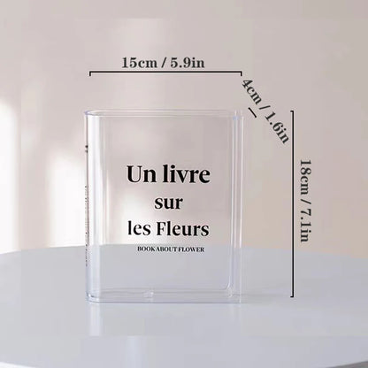 Acrylic book-shaped vase on white shelf between actual hardcover books as creative accent