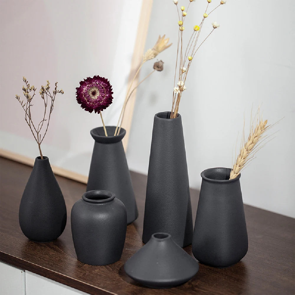 Small matte frosted ceramic bud vase style C with single dried stem on white shelf
