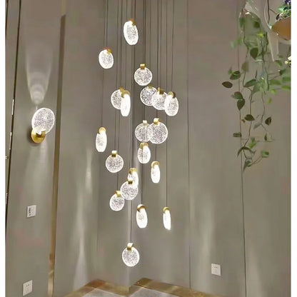 Golden crystal stair chandelier lit in warm light down a void