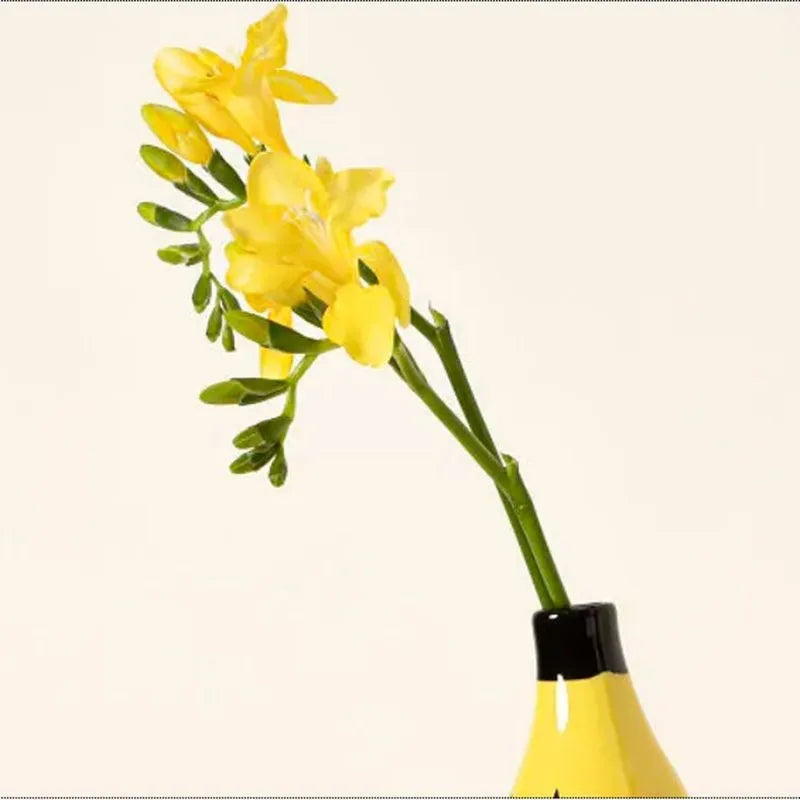 Resin banana vase with fresh flowers on eclectic maximalist desktop