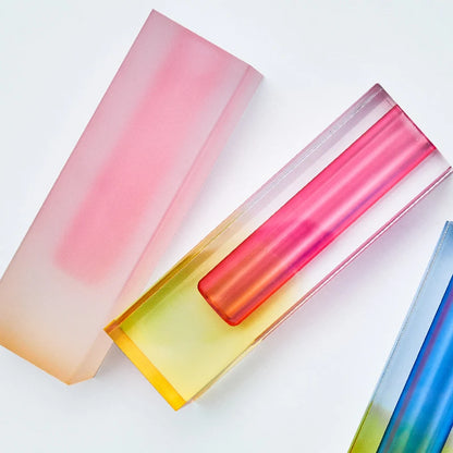 Pair of frosted pink-green acrylic pillar bud vases on a white console table