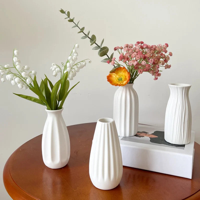 Modern white ceramic flower vase with plant stems on table