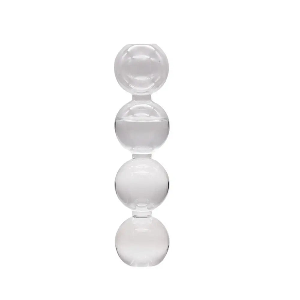 Three colored glass hydroponic vases in transparent pink and blue grouped on white shelf
