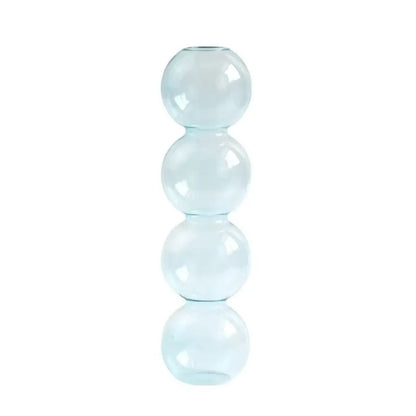 Small transparent glass hydroponic vase with white cotton stem on neutral linen surface