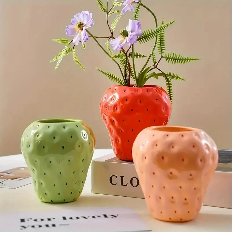 Cyan ceramic strawberry vase with dried flowers on eclectic table display