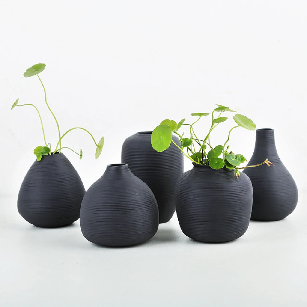 Three small black ceramic vases in styles B C and D arranged as decorative collection