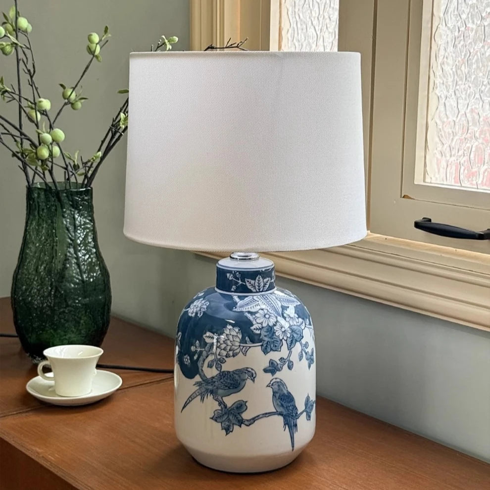 Porcelain vase lamp on hotel nightstand in soft ambient low light