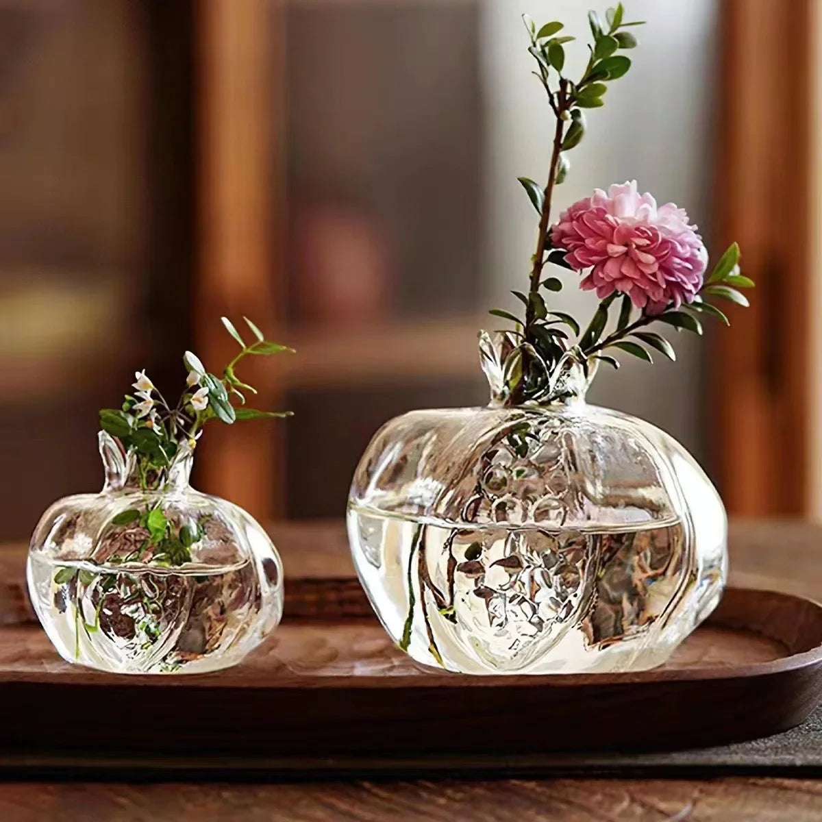 Two glass pomegranate vases side by side on shelf showing large and small size difference