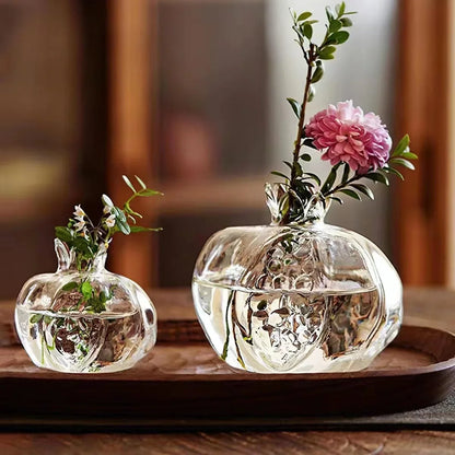 Two glass pomegranate vases side by side on shelf showing large and small size difference