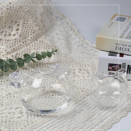 Small cat-shaped glass planter with green succulent on wooden desk