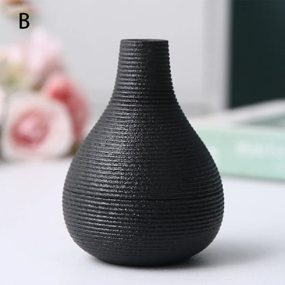 Black ceramic vase B holding single dried seed head on white floating wall shelf