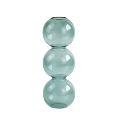 Transparent glass hydroponic bud vase flat lay on concrete surface with plant cuttings