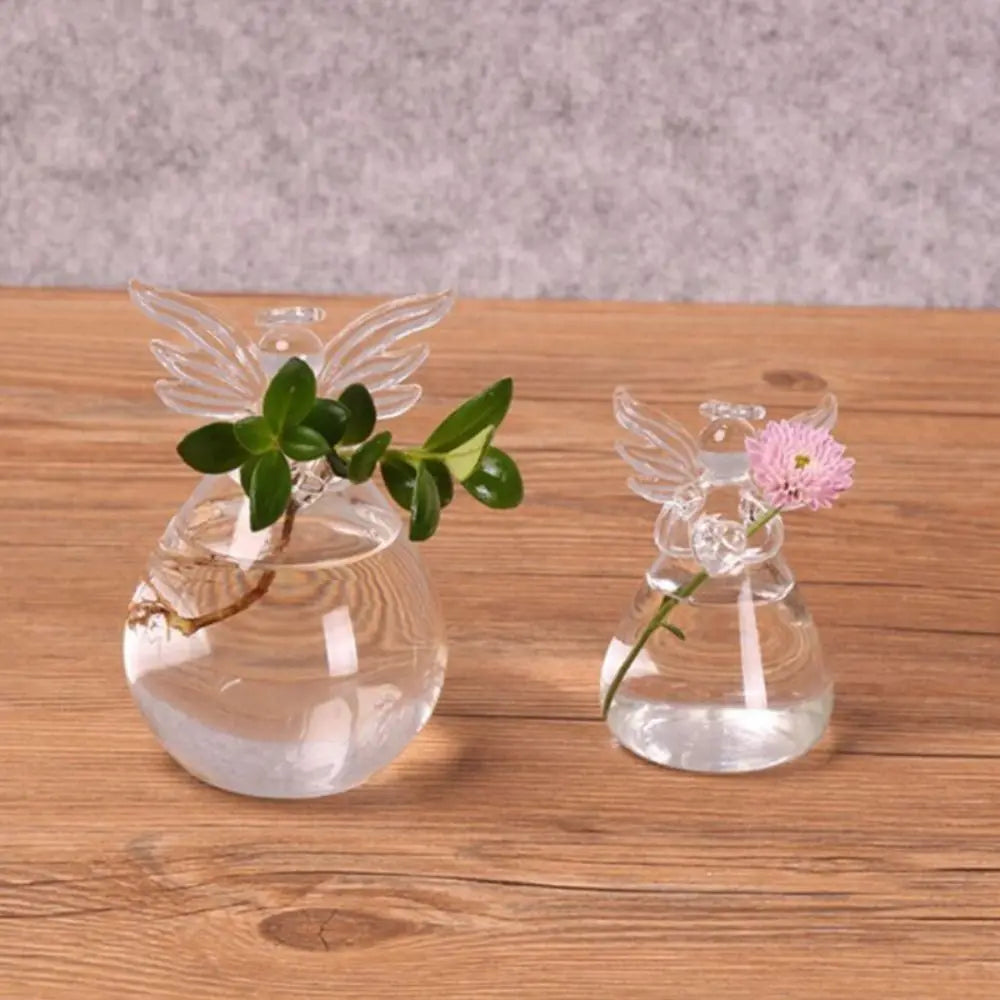 Hand-blown angel shape glass vase with plant on white wall