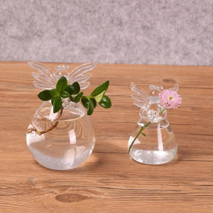Hand-blown angel shape glass vase with plant on white wall