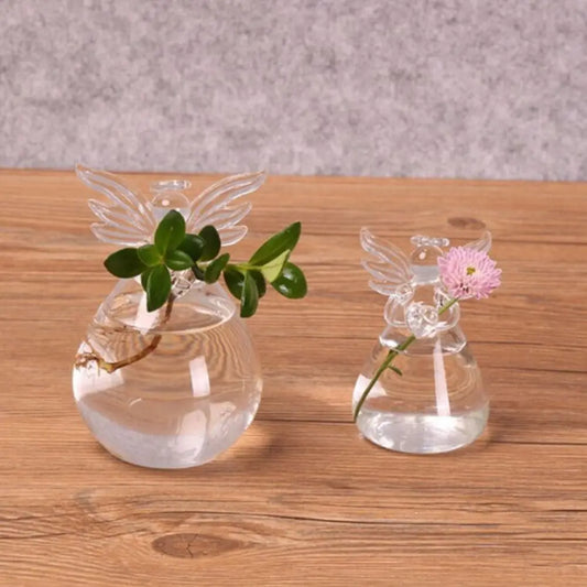 Hand-blown angel shape glass vase with plant on white wall