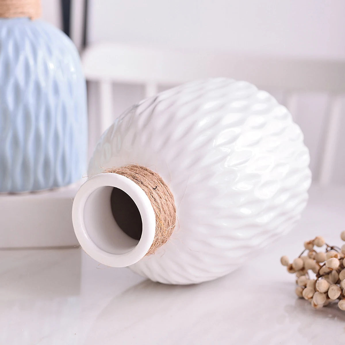 White ripple-textured plastic Nordic vase holding dried botanical stems on desk