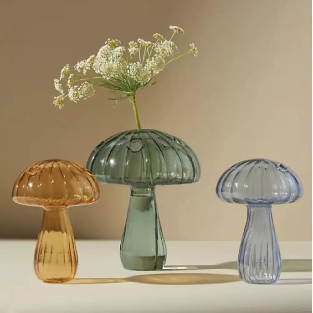 Light green mushroom-shaped glass bud vase on wooden desk with single stem