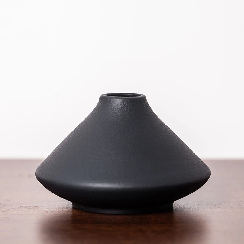 Small frosted ceramic bud vase on a windowsill catching soft natural morning light