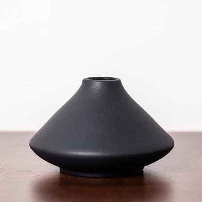 Small frosted ceramic bud vase on a windowsill catching soft natural morning light