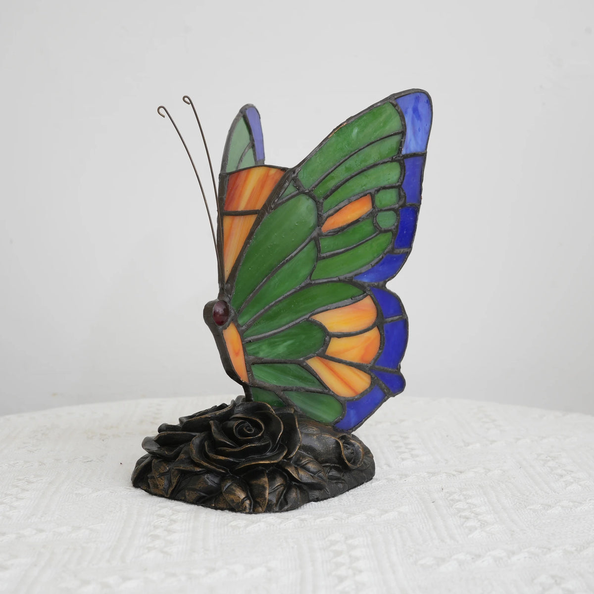 Butterfly stained glass lamp illuminated jewel tones in bedroom setting