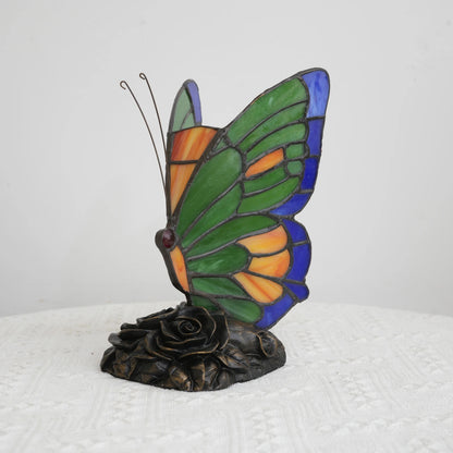 Butterfly stained glass lamp illuminated jewel tones in bedroom setting