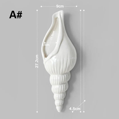 White ceramic conch vase displayed on a bright coastal-style gallery wall